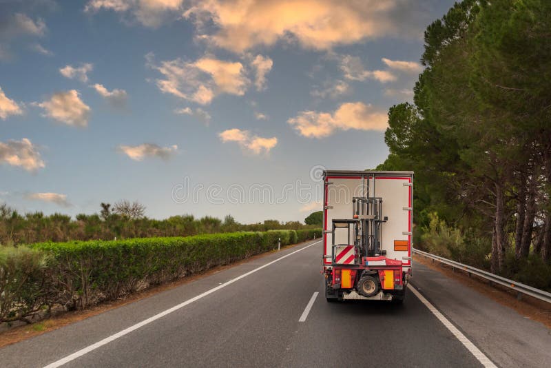 Truck with orange panel of dangerous goods with a forklift attached to its rear to do its own loading unloading, rear view stock photo
