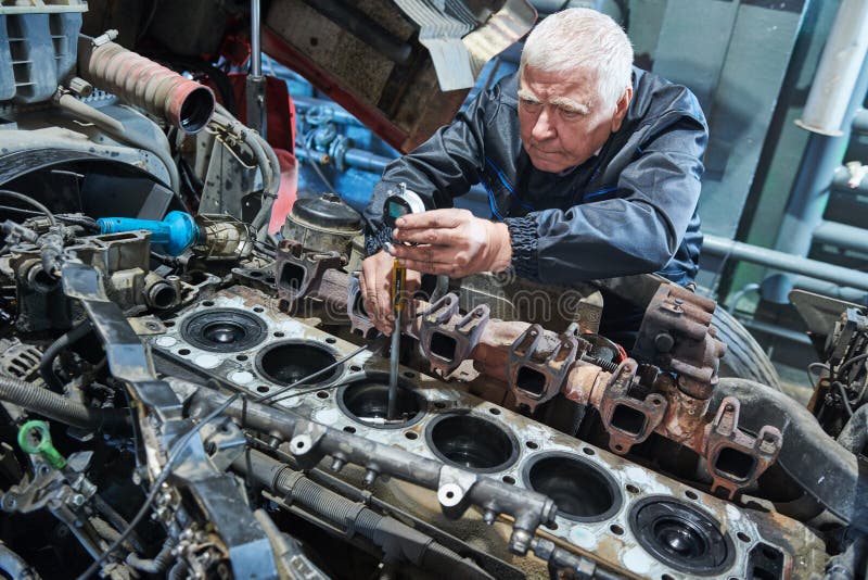 Truck repair service. Serviceman measuring cylinder