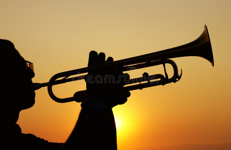 Silhouettes of trumpet player at sunset.