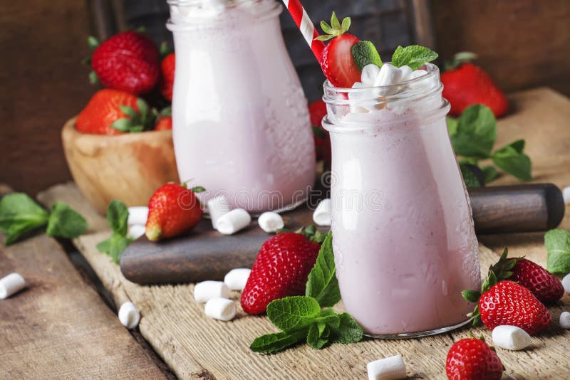 Truskawkowi smoothies i koktajle z świeżą jagodą i zielenią wybijają monety, dekorujący marshmallows, lato napój, drewniany stary obraz stock Truskawkowi smoothies i koktajle z świeżą jagodą i zielenią wybijają monety, dekorujący marshmallows, lato napój, drewniany stary obraz stock