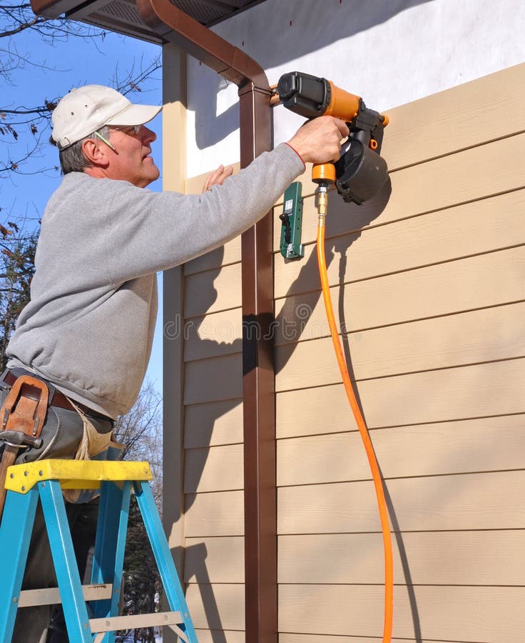 trycksprutan som installerar mannen, spikar sidingen royaltyfria bilder trycksprutan som installerar mannen, spikar sidingen royaltyfria bilder