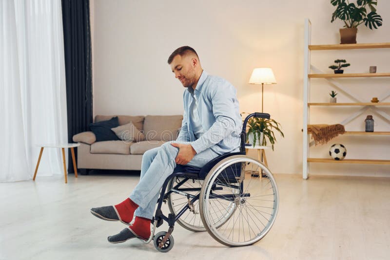 Trying To Move. Disabled Man in Wheelchair is at Home Stock Image