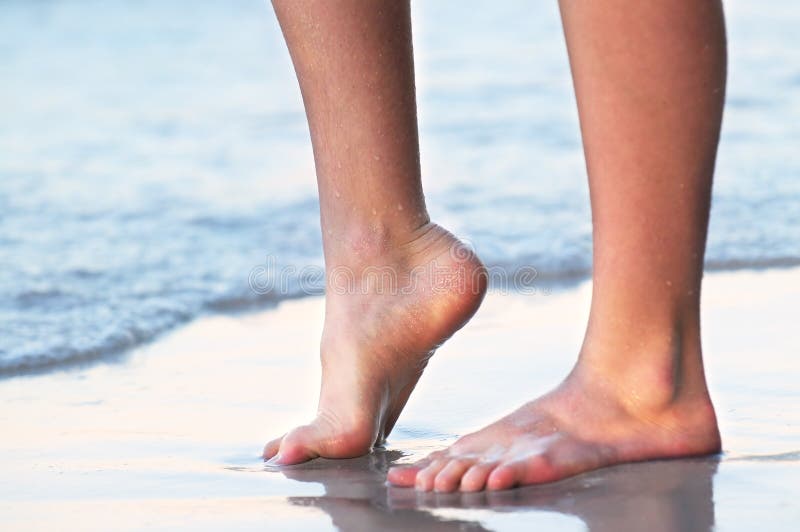 Feet of a young woman touching water on tropical beach. Feet of a young woman touching water on tropical beach