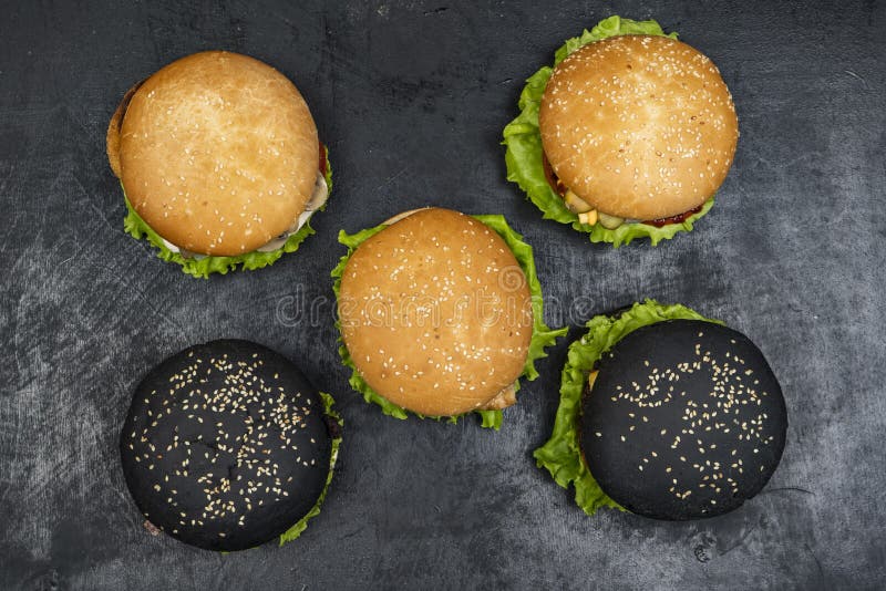 Trzy hamburger z wołowina mięsnym hamburgerem i świeżymi warzywami na ciemnym tle Smakowity jedzenie fotografia stock Trzy hamburger z wołowina mięsnym hamburgerem i świeżymi warzywami na ciemnym tle Smakowity jedzenie fotografia stock