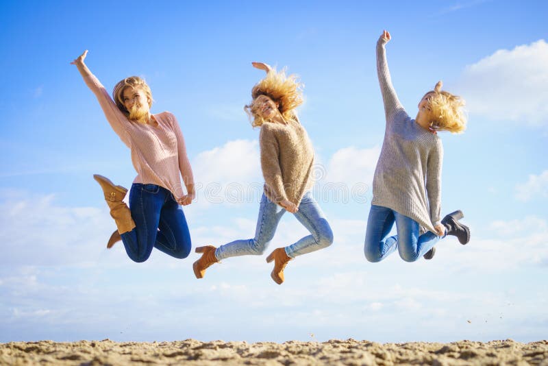 Trzy kobiet skaka?. Three women full of joy jumping around with sky in background. Female friends having fun outdoor