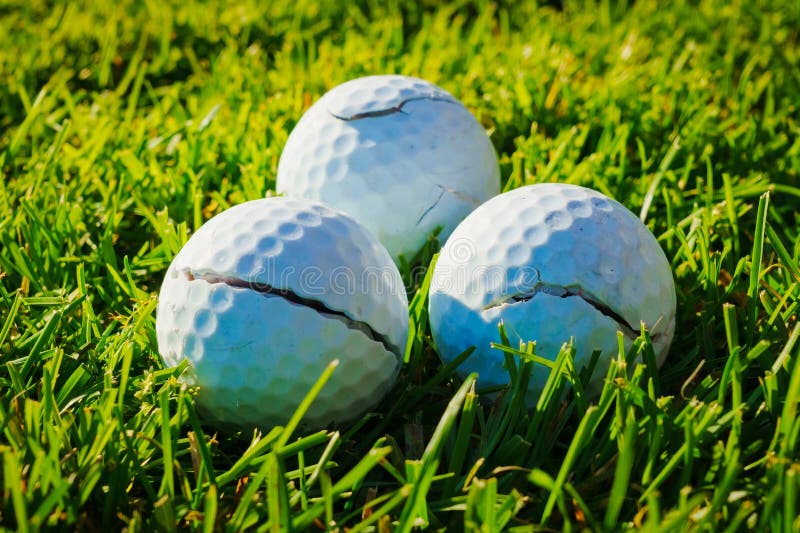 Trzy rozszczepione białe piłki golfowe na zielonej trawie. wiele uszkodzonych piłeczek golfowych bliskie zdjęcie fotografia royalty free
