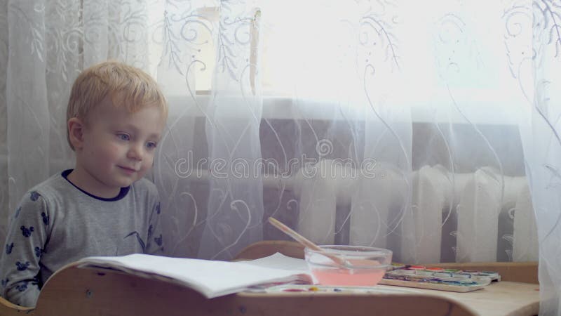 Trzyletni kaukaski chłopiec rysujący z piórem. mały chłopiec bawiący się malarstwem obraz na papierze. dzieciak