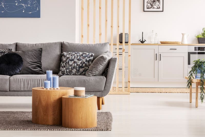 Träform för kvarter två som kaffetabeller med kinckknepar framme av den gråa scandinavian soffan med kuddar royaltyfri foto Träform för kvarter två som kaffetabeller med kinckknepar framme av den gråa scandinavian soffan med kuddar royaltyfri foto