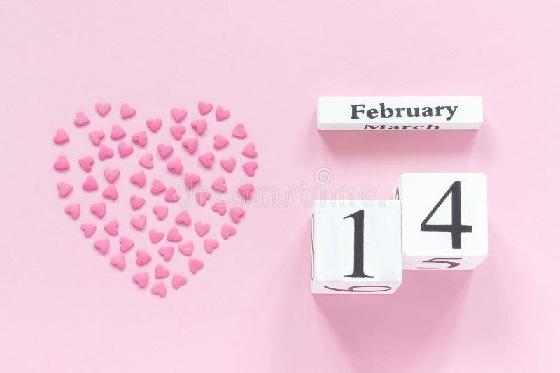 Träkubkalender Februari 14th och hjärta från rosa konfektstänk i en hjärtaform på pastellfärgad rosa bakgrund royaltyfri fotografi Träkubkalender Februari 14th och hjärta från rosa konfektstänk i en hjärtaform på pastellfärgad rosa bakgrund royaltyfri fotografi