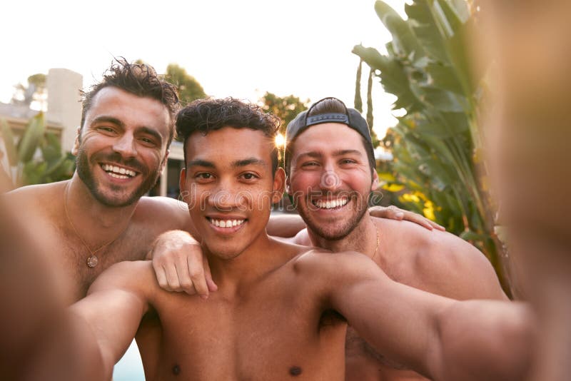 Três amigos do sexo masculino na festa da piscina de verão tomando selfie no telefone celular