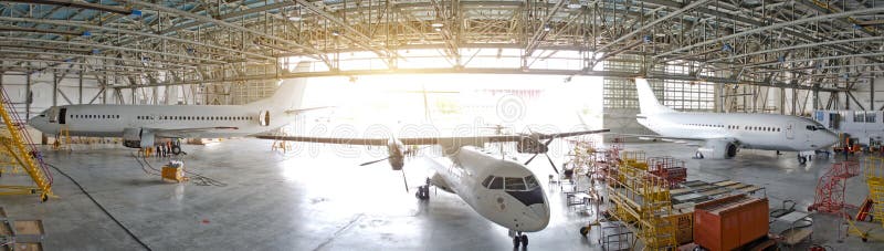 Três aviões de passageiro em um hangar com uma porta aberta para o serviço, ideia do panorama fotos de stock royalty free Três aviões de passageiro em um hangar com uma porta aberta para o serviço, ideia do panorama fotos de stock royalty free