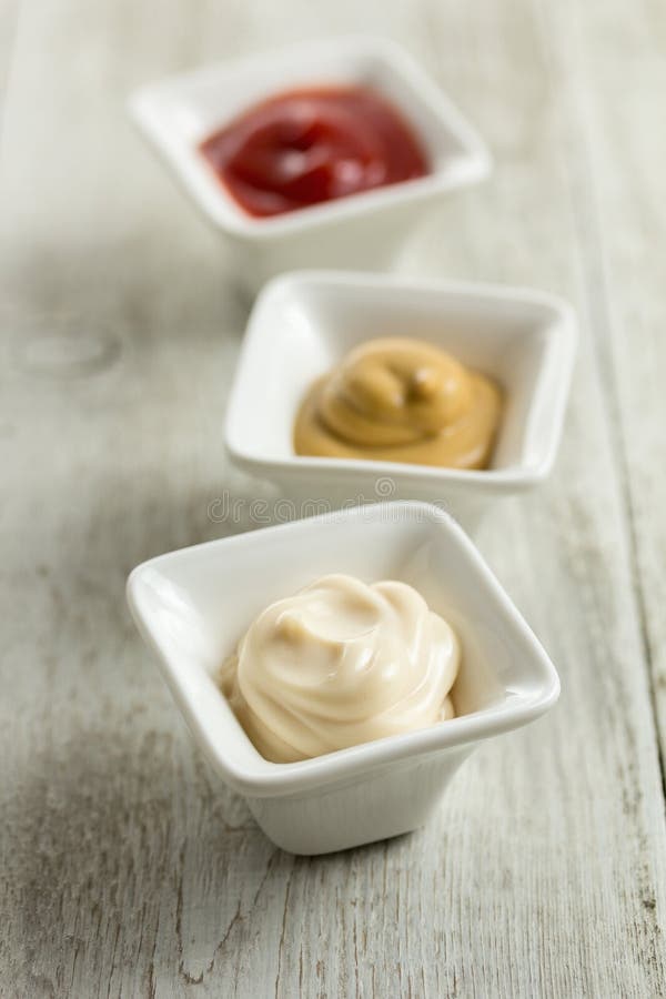 Three condiment bowls with ketchup, mustard, and mayonnaise. Three condiment bowls with ketchup, mustard, and mayonnaise