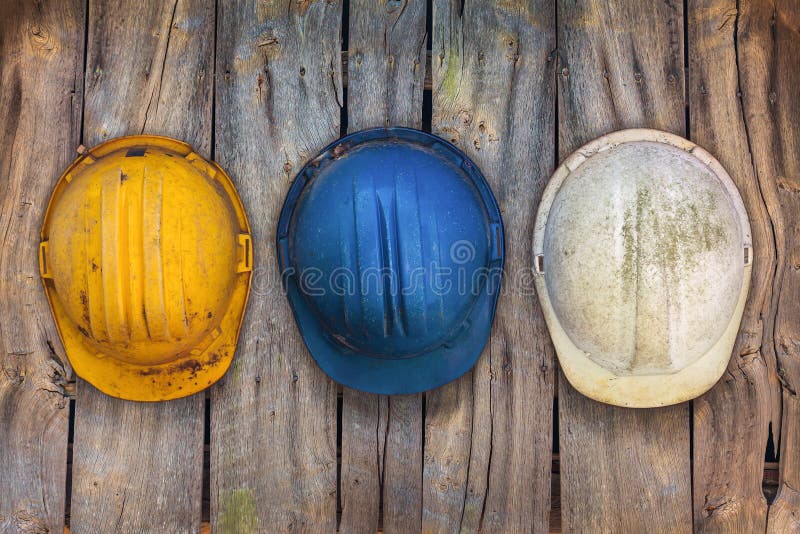 Três capacetes da construção do vintage em uma parede de madeira foto de stock royalty free Três capacetes da construção do vintage em uma parede de madeira foto de stock royalty free