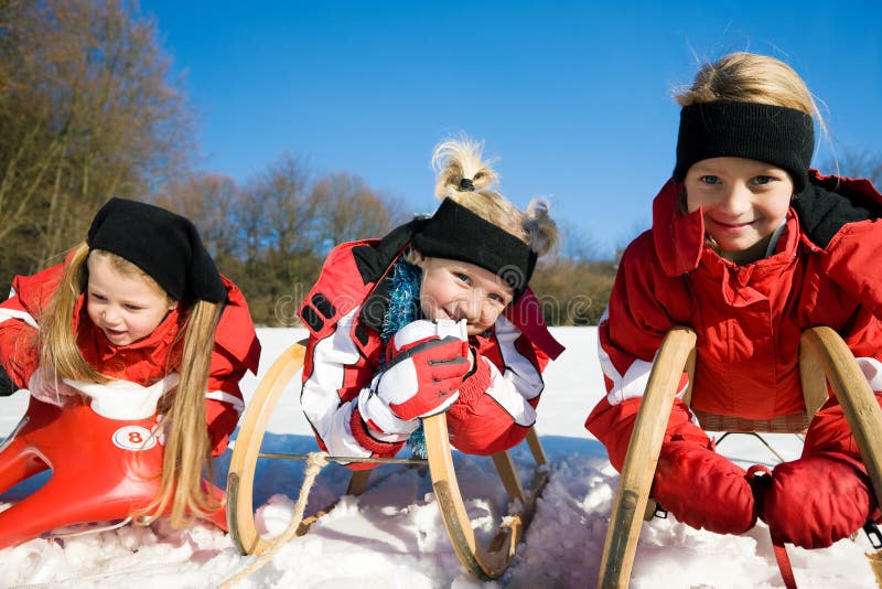 Três crianças com o toboggan na neve foto de stock royalty free Três crianças com o toboggan na neve foto de stock royalty free