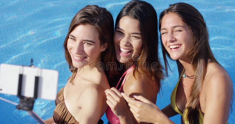 Três jovens mulheres bonitas que levantam para um selfie