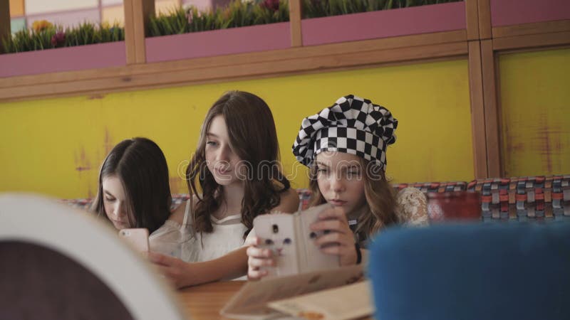 Três meninas consideravelmente alegres que tomam selfies no café 4K