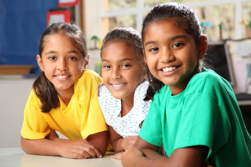 Três meninas novas da escola preliminar que sentam-se na classe imagens de stock Três meninas novas da escola preliminar que sentam-se na classe imagens de stock