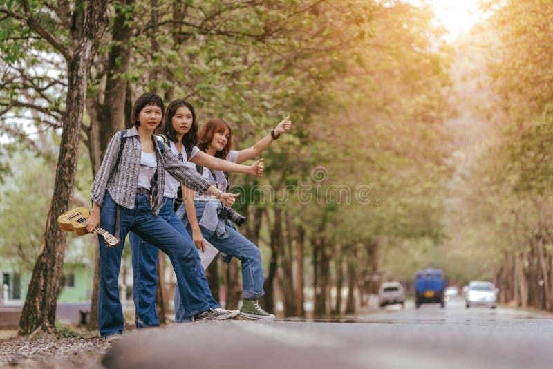 Três mochileiros inter-raciais novos felizes da menina, compartilhando de um passeio em férias fotografia de stock royalty free Três mochileiros inter-raciais novos felizes da menina, compartilhando de um passeio em férias fotografia de stock royalty free