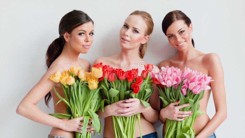 Três mulheres bonitas com as tulipas frescas da mola