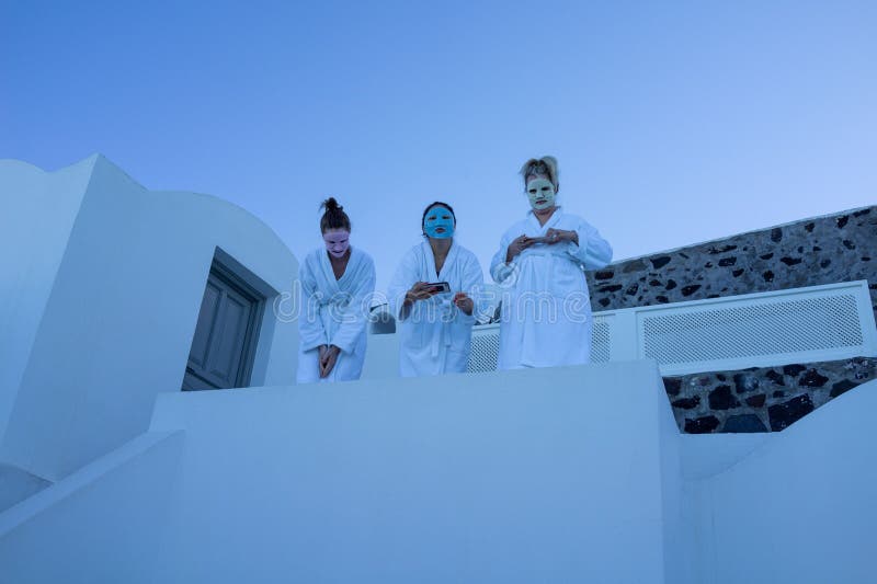 The three women in face masks and robes standing in a white building in Santorini, Greece. The three women in face masks and robes standing in a white building in Santorini, Greece.