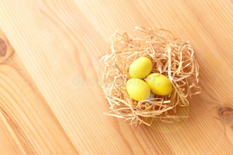 Três ovos amarelos em um ninho em um fundo de madeira claro A Páscoa comemora o conceito fotografia de stock Três ovos amarelos em um ninho em um fundo de madeira claro A Páscoa comemora o conceito fotografia de stock