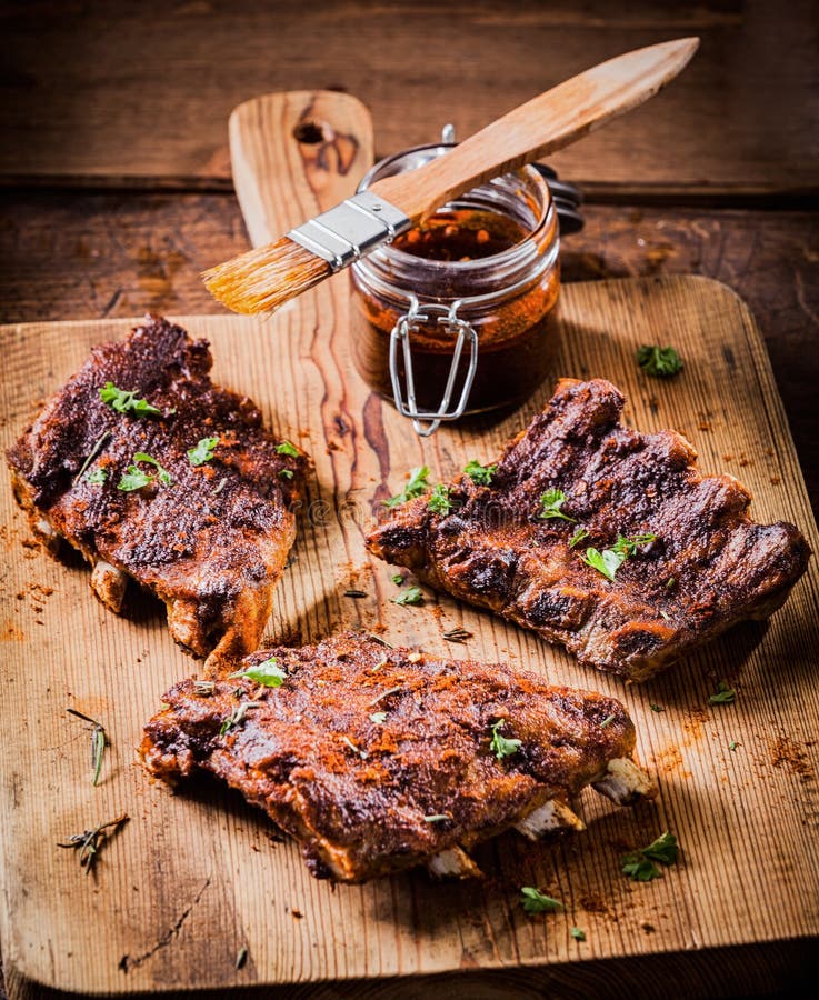 Three portions of spicy grilled ribs basted with a savory aromatic sauce and garnished with herbs for a delicious meal. Three portions of spicy grilled ribs basted with a savory aromatic sauce and garnished with herbs for a delicious meal