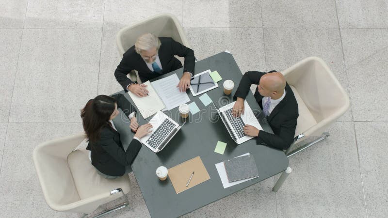 Três povos de empresa que encontram-se no escritório usando laptop
