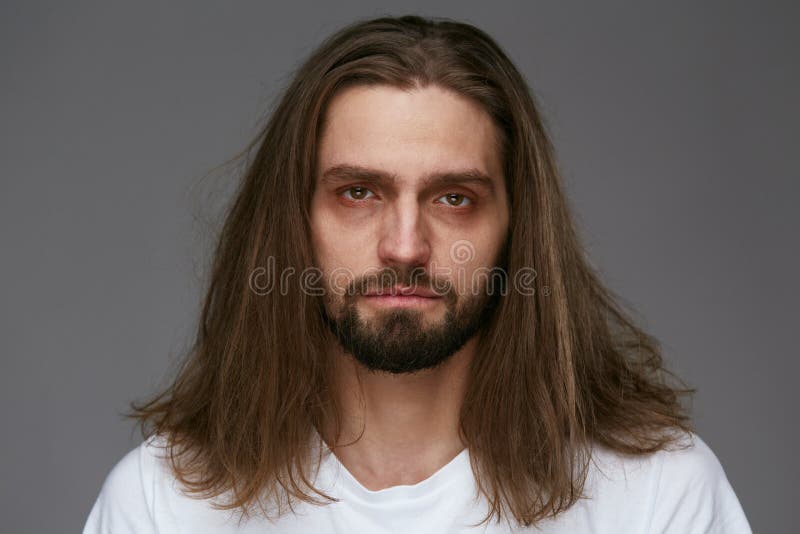 Tired Man With Exhausted Face And Dark Circles Under Eyes And Long Hair On Gray Background. High Resolution. Tired Man With Exhausted Face And Dark Circles Under Eyes And Long Hair On Gray Background. High Resolution.