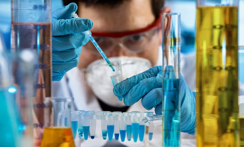 Tubo de ensayo de la tenencia del investigador para el análisis con el material del químico en el laboratorio de la investigación fotografía de archivo Tubo de ensayo de la tenencia del investigador para el análisis con el material del químico en el laboratorio de la investigación fotografía de archivo