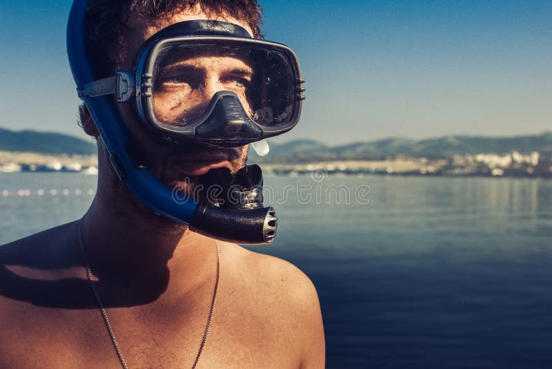 Tubo de respiração masculino de With Mask And do mergulhador de mergulhador que está na praia no fundo da costa de mar imagem de stock royalty free Tubo de respiração masculino de With Mask And do mergulhador de mergulhador que está na praia no fundo da costa de mar imagem de stock royalty free