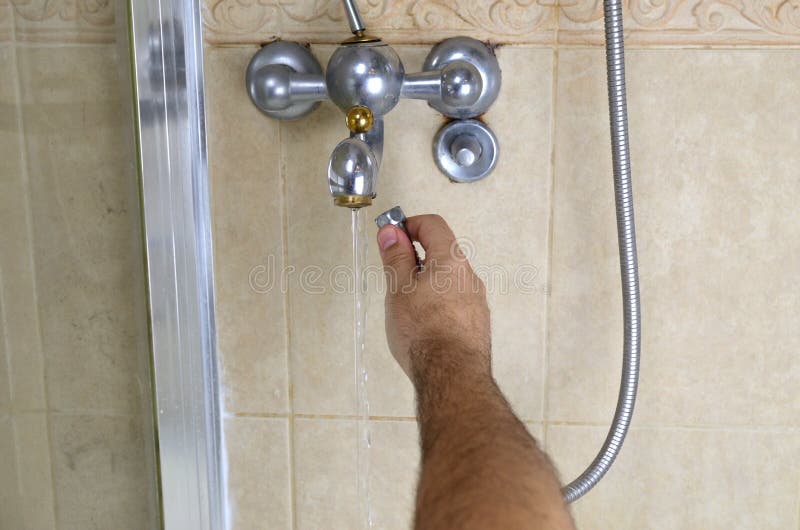 Man`s hand changing shower hose on a bathroom tap. Man`s hand changing shower hose on a bathroom tap