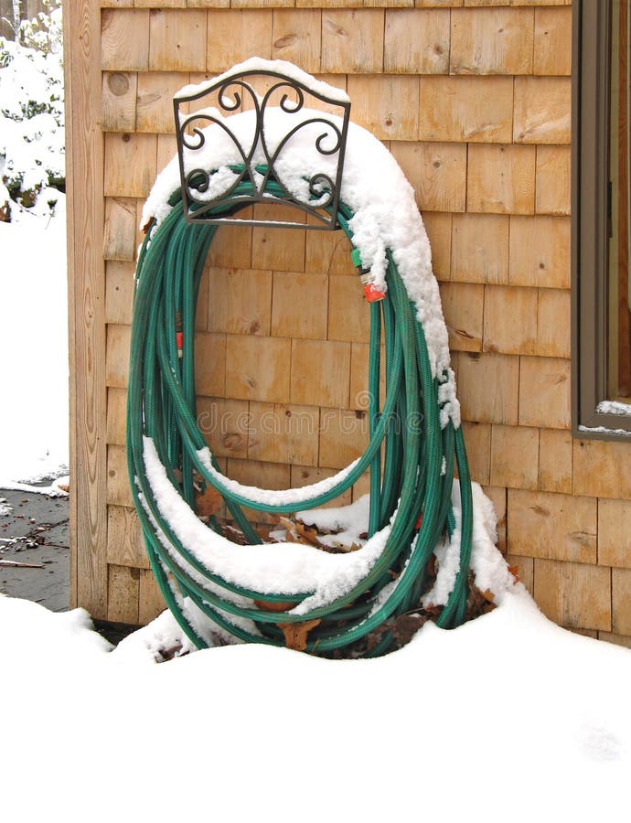 Garden hose in decorative holder, topped by winter snow. Garden hose in decorative holder, topped by winter snow