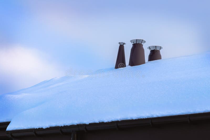 Tubos del metal del sistema de ventilación en el tejado del edificio cubierto con nieve foto de archivo Tubos del metal del sistema de ventilación en el tejado del edificio cubierto con nieve foto de archivo