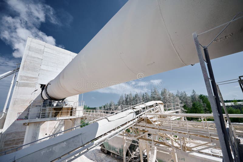 Tubular rotary furnace for calx clinker and cement processing at industrial plant. Manufacturing complex of silica products under blue sky. Tubular rotary furnace for calx clinker and cement processing at industrial plant. Manufacturing complex of silica products under blue sky