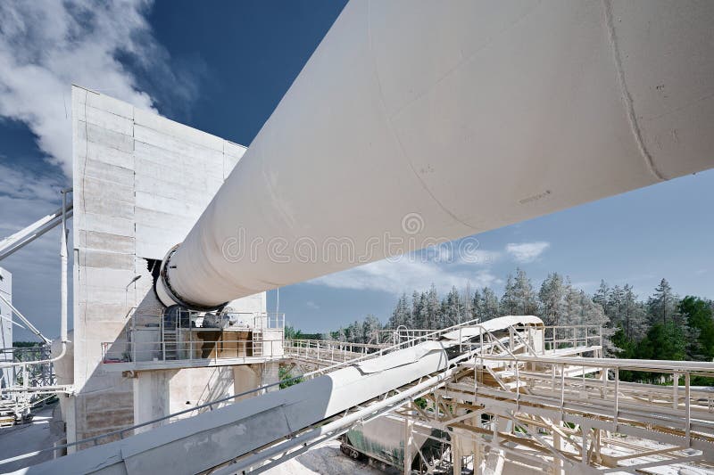 Tubular rotary furnace for calx clinker and cement processing at industrial plant. Manufacturing complex of silica products under blue sky. Tubular rotary furnace for calx clinker and cement processing at industrial plant. Manufacturing complex of silica products under blue sky