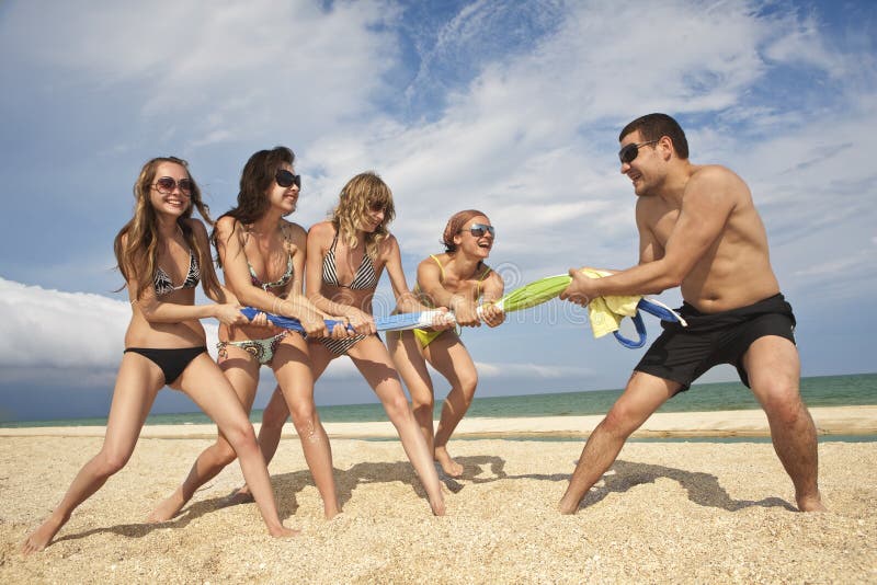 Tug-of-war between girls and guy on the beach. Tug-of-war between girls and guy on the beach