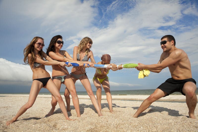 Tug-of-war between girls and guy on the beach. Tug-of-war between girls and guy on the beach