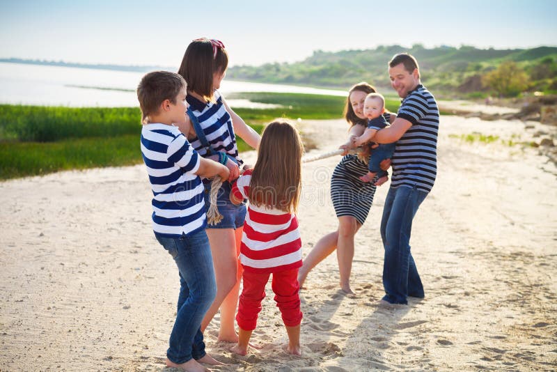 Tug of war - family playing on the beach. Summer holiday and family power concept