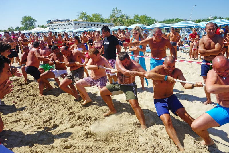 Team of men in swimsuit competing in a tug of war on the beach. Team of men in swimsuit competing in a tug of war on the beach