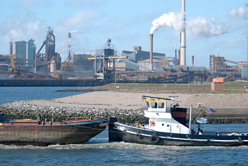 Tugboat pushing cargo ship in harbor