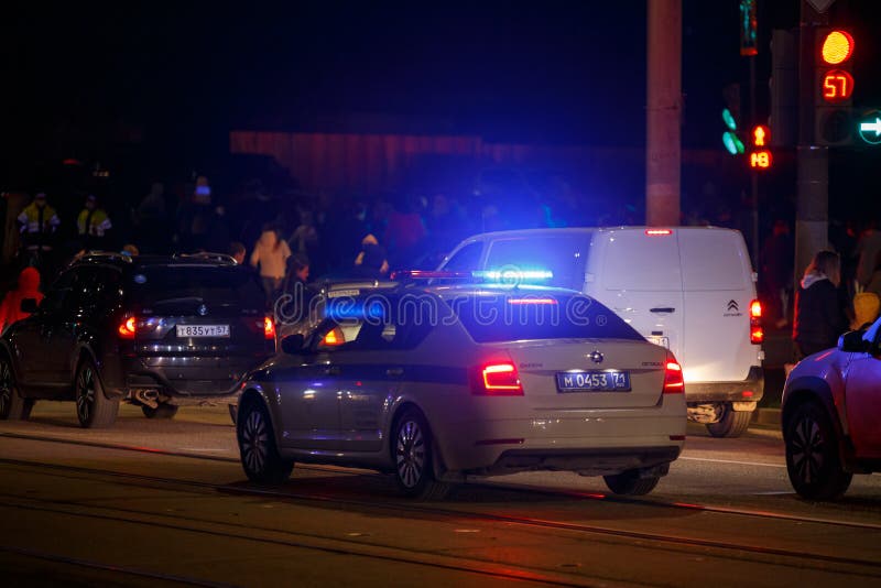 Tula, Russia - May 9, 2021: Police car with turned on red and blue siren light on its roof on night city road. Tula, Russia - May 9, 2021: Police car with turned on red and blue siren light on its roof on night city road.