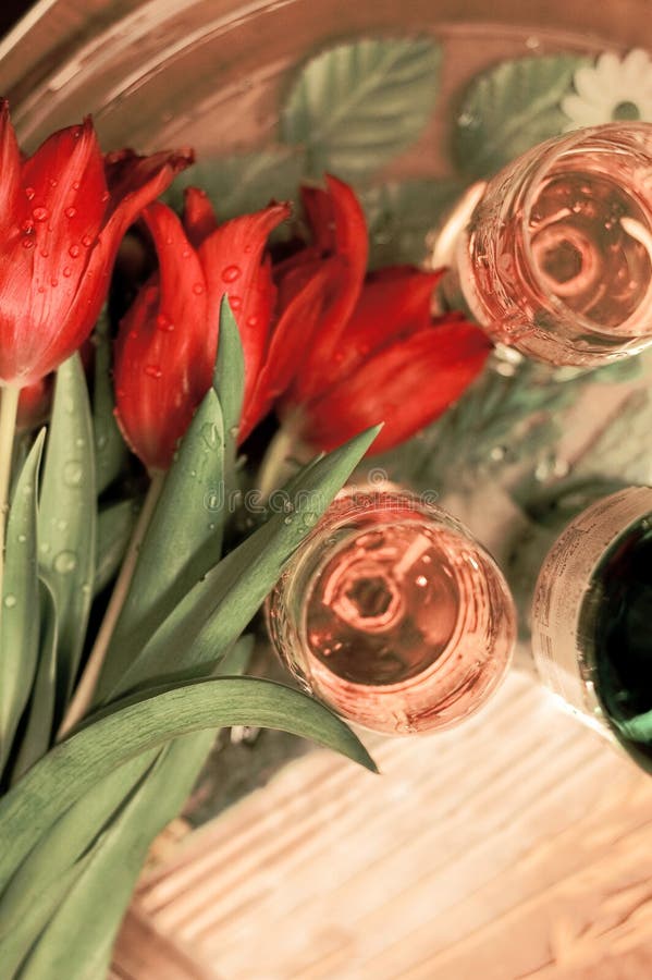 Tulipani rossi nei waterdrops con i bicchieri di vino fotografia stock