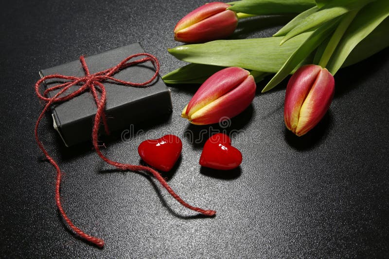 Tulpan, gåvaask och röda hjärtor arkivbild