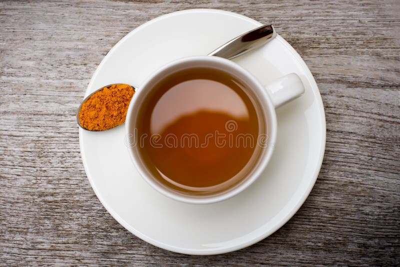 Closeup White Ceramic Cup of Hot Turmeric Tea with Tumeric Powder Stock
