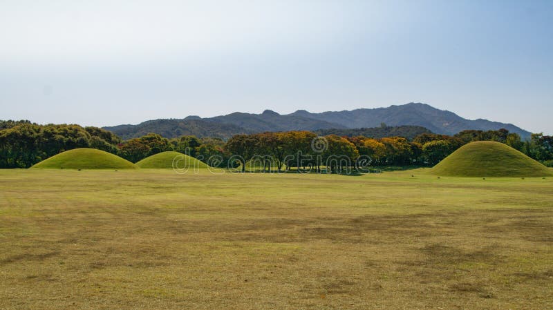 Tumuli royal tomb in autumn foliage backgroung. Gyeongju, South Korea.The Gyeongju Historic Areas of South Korea were designated as a World Heritage Site by UNESCO in 2000, ref 976.