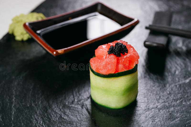 Eating delicious food. Chopsticks taking sushi roll from plate. Seafood  delicatessen salmon gunkan maki on wooden platter. Delicacy gourmet snacks.  Luxury lifestyle, expensive food, restaurant menu Stock Photo