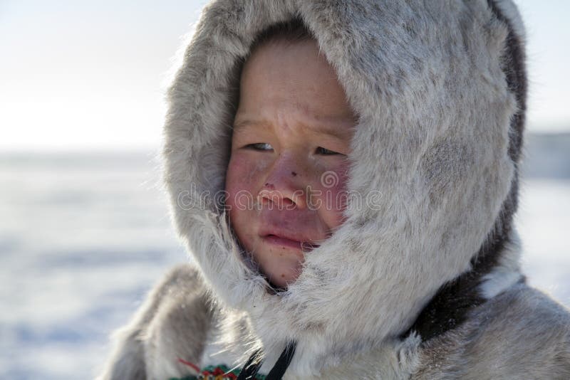 Tundra, open area, the boy looking afar in cold winter weather, the boy in a national clothes, the sad look of the child, portrait. Tundra, open area, the boy looking afar in cold winter weather, the boy in a national clothes, the sad look of the child, portrait.