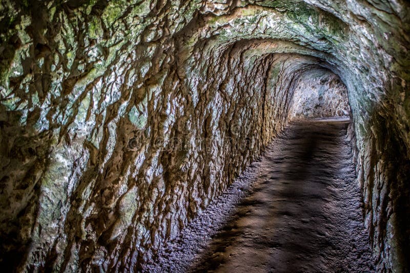 Tunnel scuro della caverna del passaggio pedonale del passeggero della roccia e della sporcizia immagini stock libere da diritti Tunnel scuro della caverna del passaggio pedonale del passeggero della roccia e della sporcizia immagini stock libere da diritti