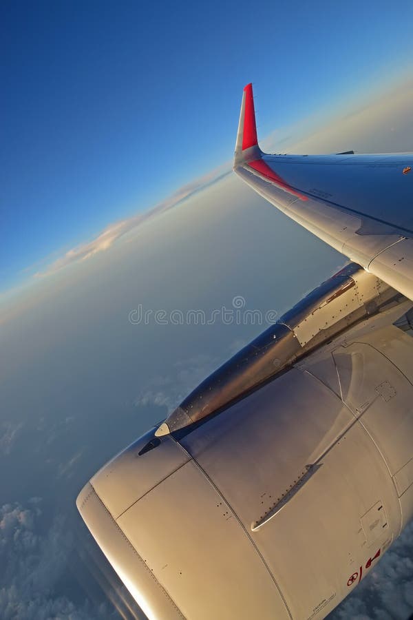 Turbinemotor, vleugel en rode winglet met witte wolken en diepe blauwe hemel op de achtergrond royalty-vrije stock fotografie Turbinemotor, vleugel en rode winglet met witte wolken en diepe blauwe hemel op de achtergrond royalty-vrije stock fotografie