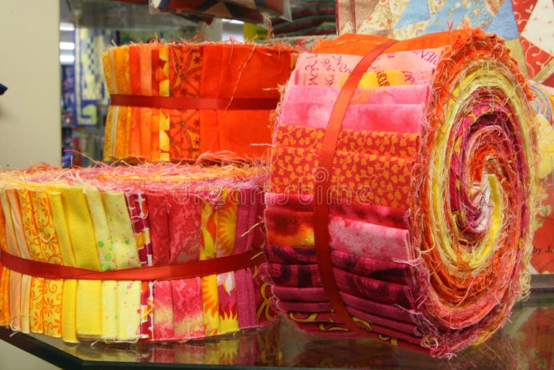 Closeup of pre-cut quilt fabric bundled together in a colorful swirl of yellow, orange and red colors and designs. Closeup of pre-cut quilt fabric bundled together in a colorful swirl of yellow, orange and red colors and designs